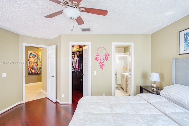 bedroom featuring ceiling fan, ensuite bathroom, hardwood / wood-style floors, a walk in closet, and a closet