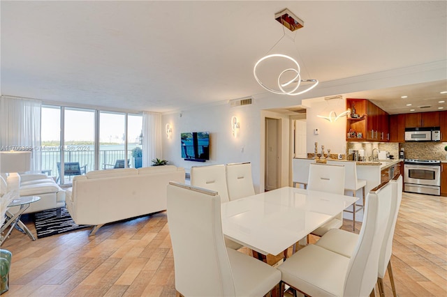 dining space featuring light wood-type flooring and ornamental molding