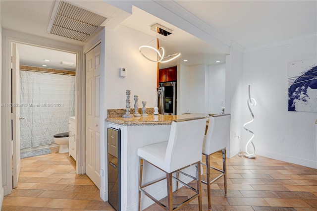 kitchen with kitchen peninsula, stainless steel fridge, a kitchen breakfast bar, decorative light fixtures, and light hardwood / wood-style floors