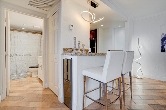 interior space featuring light stone countertops, stainless steel fridge, a breakfast bar, tile walls, and ornamental molding