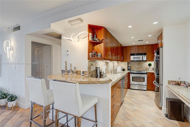 kitchen featuring a kitchen breakfast bar, sink, ornamental molding, appliances with stainless steel finishes, and kitchen peninsula