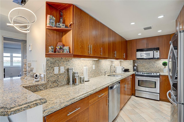 kitchen featuring backsplash, stainless steel appliances, light stone counters, and sink