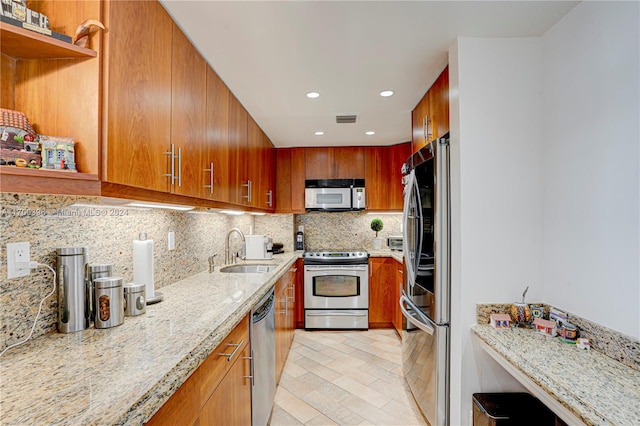 kitchen featuring decorative backsplash, light stone countertops, sink, and appliances with stainless steel finishes