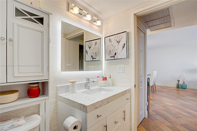 bathroom with hardwood / wood-style floors, vanity, and toilet