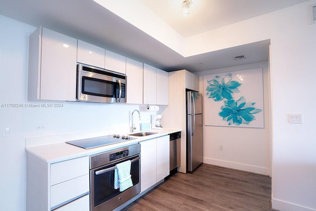 kitchen featuring white cabinets, hardwood / wood-style flooring, sink, and appliances with stainless steel finishes