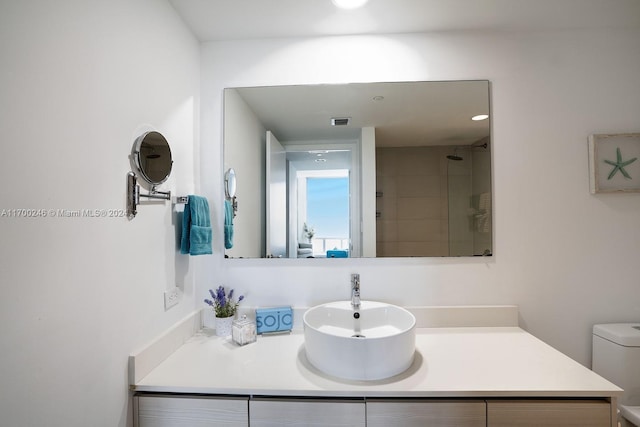 bathroom with tiled shower, vanity, and toilet