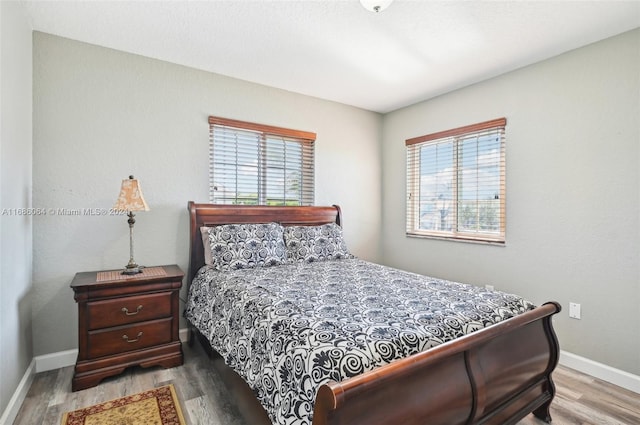 bedroom with multiple windows and hardwood / wood-style flooring