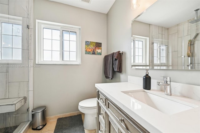 bathroom featuring tile patterned flooring, a tile shower, vanity, and toilet