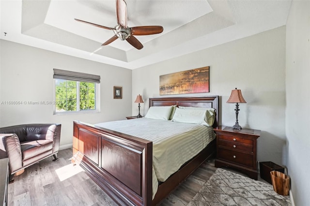 bedroom featuring hardwood / wood-style floors, ceiling fan, and a tray ceiling