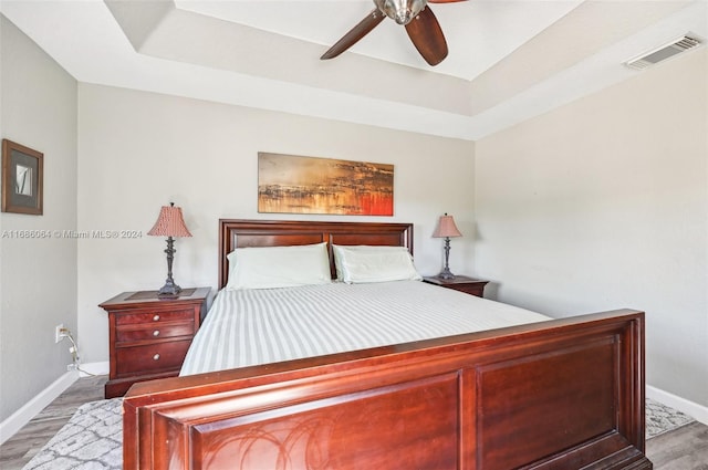 bedroom with a tray ceiling, ceiling fan, and light hardwood / wood-style floors