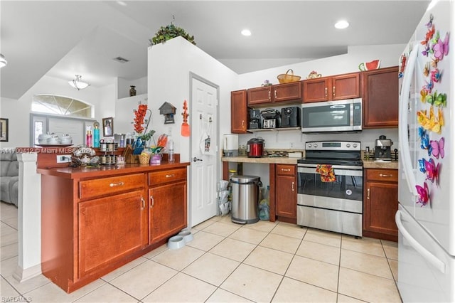 kitchen featuring appliances with stainless steel finishes, lofted ceiling, and light tile patterned flooring