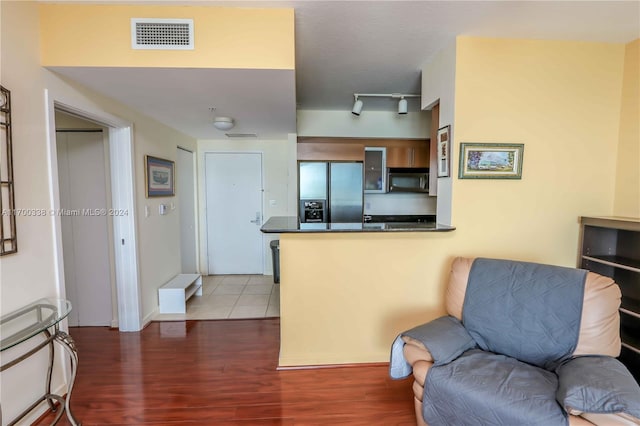 interior space with rail lighting, dark hardwood / wood-style flooring, kitchen peninsula, and stainless steel refrigerator with ice dispenser