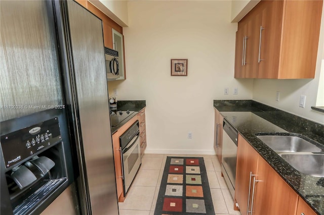 kitchen featuring black appliances, dark stone countertops, light tile patterned floors, and sink