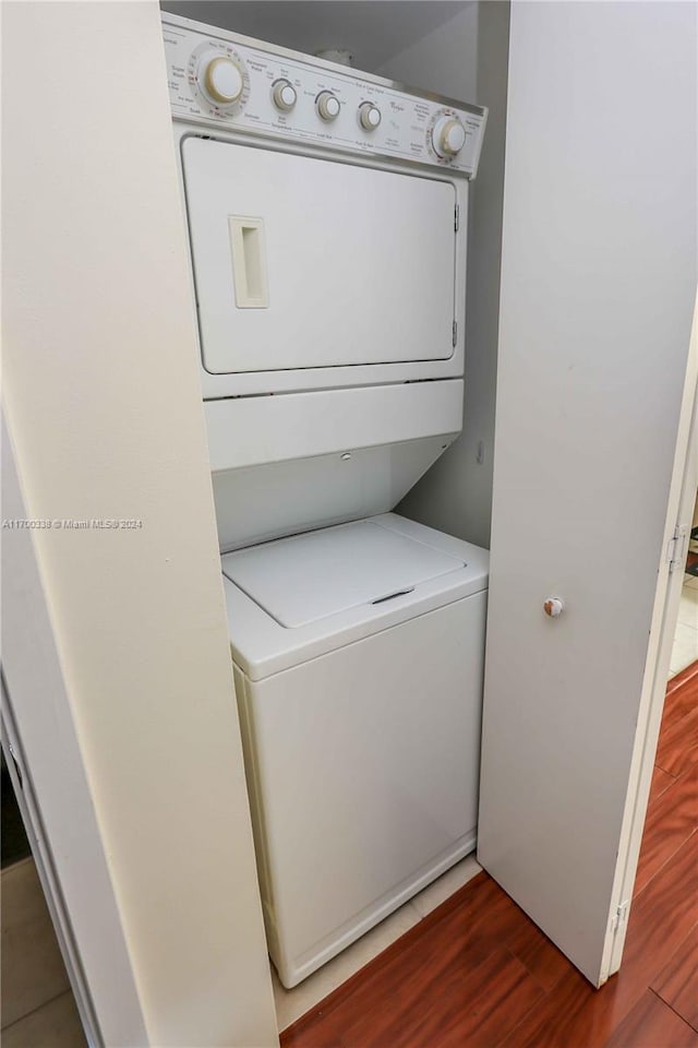 laundry room with dark hardwood / wood-style floors and stacked washer and clothes dryer