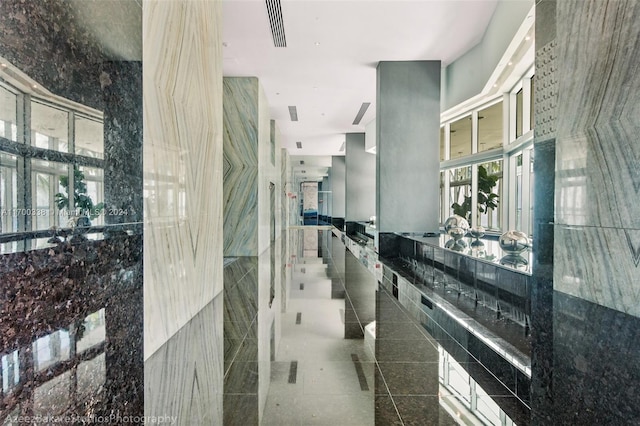 hall with dark tile patterned flooring and tile walls