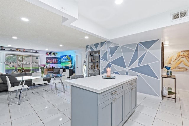 kitchen with a center island, gray cabinets, light tile patterned floors, and a textured ceiling