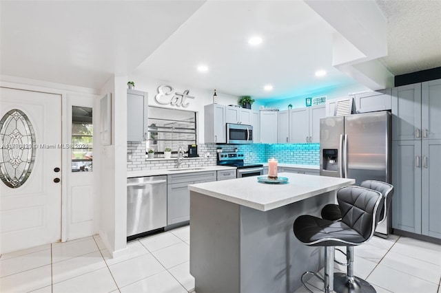 kitchen featuring a center island, a kitchen breakfast bar, sink, decorative backsplash, and appliances with stainless steel finishes