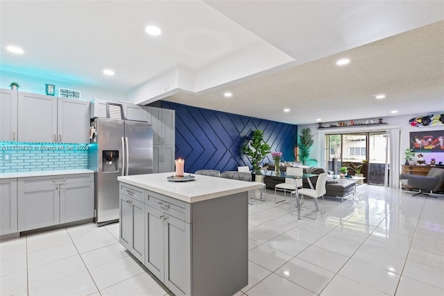 kitchen featuring gray cabinets, stainless steel fridge with ice dispenser, a center island, and light tile patterned floors