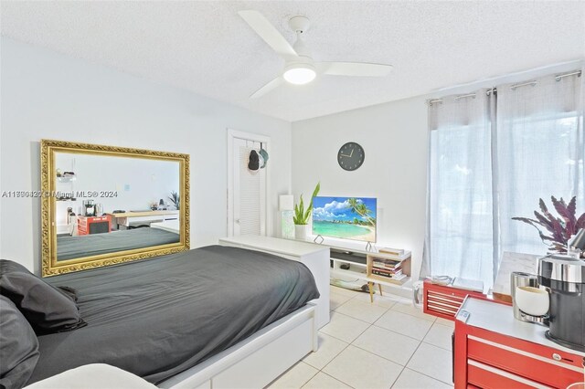 tiled bedroom with multiple windows, ceiling fan, and a textured ceiling