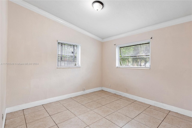 empty room with light tile patterned floors, vaulted ceiling, a wealth of natural light, and ornamental molding