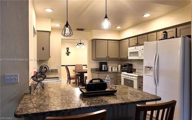 kitchen featuring decorative light fixtures, a kitchen bar, white appliances, and sink