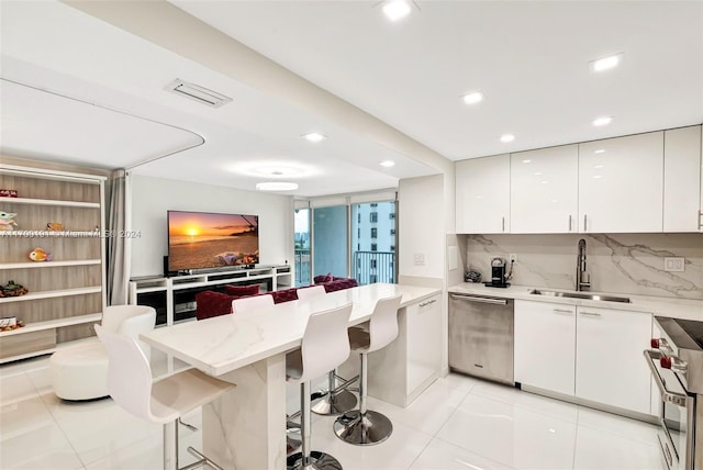 kitchen featuring white cabinetry, sink, backsplash, a breakfast bar area, and appliances with stainless steel finishes