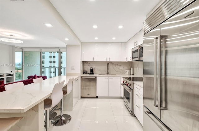 kitchen featuring backsplash, white cabinetry, a breakfast bar, and high end appliances