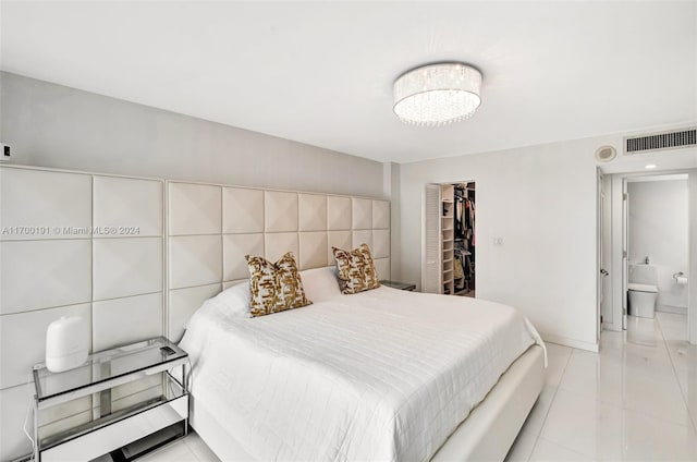 bedroom with ensuite bathroom, a walk in closet, a closet, light tile patterned flooring, and tile walls