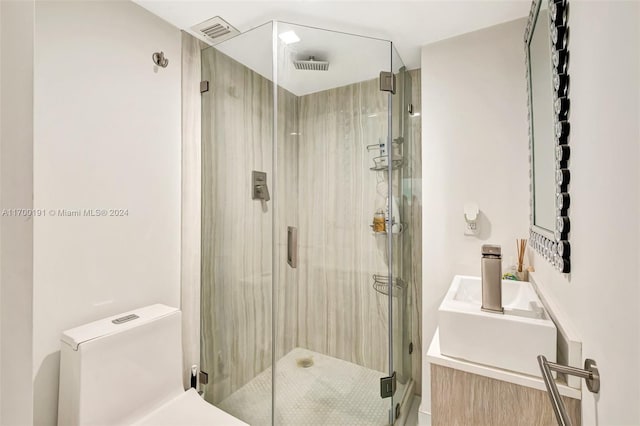 bathroom featuring vanity, a shower with shower door, and toilet