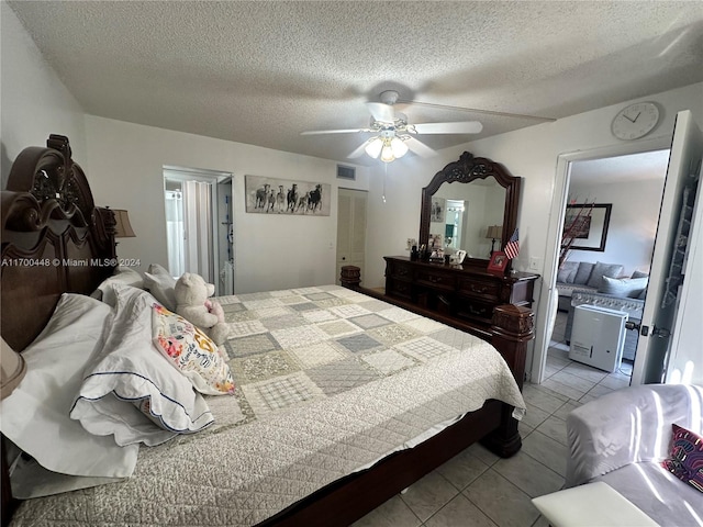 bedroom featuring light tile patterned floors, a textured ceiling, ensuite bath, and ceiling fan