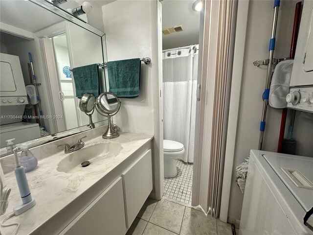 bathroom with tile patterned flooring, vanity, toilet, and stacked washing maching and dryer