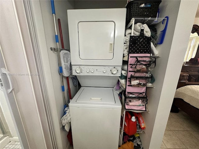 laundry area with stacked washing maching and dryer and light tile patterned floors