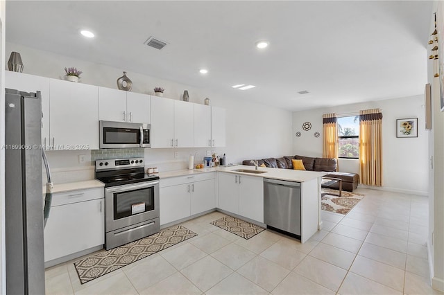 kitchen with sink, kitchen peninsula, white cabinets, and appliances with stainless steel finishes