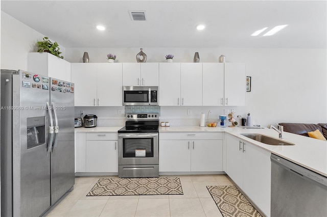 kitchen with white cabinetry, sink, light tile patterned floors, and stainless steel appliances