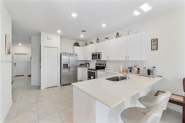 kitchen with stainless steel appliances, sink, a kitchen bar, and kitchen peninsula