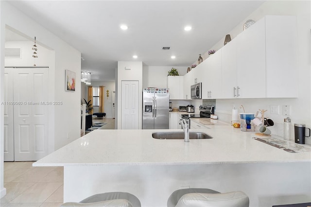 kitchen featuring sink, white cabinets, a kitchen bar, kitchen peninsula, and stainless steel appliances