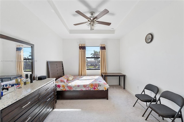 bedroom featuring light carpet, a raised ceiling, and ceiling fan