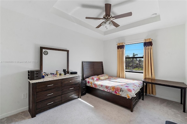 bedroom featuring ceiling fan, light colored carpet, and a raised ceiling