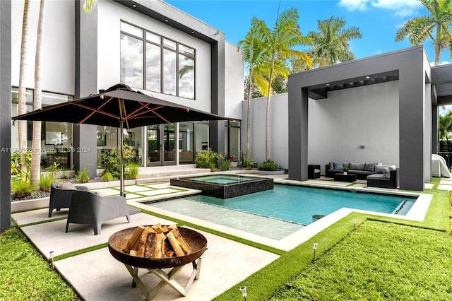 rear view of property with a patio area, an outdoor living space with a fire pit, and a pool with hot tub