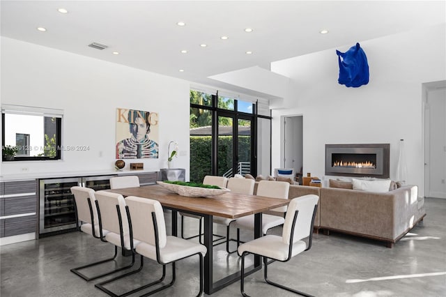 dining area with beverage cooler, concrete flooring, and a high ceiling