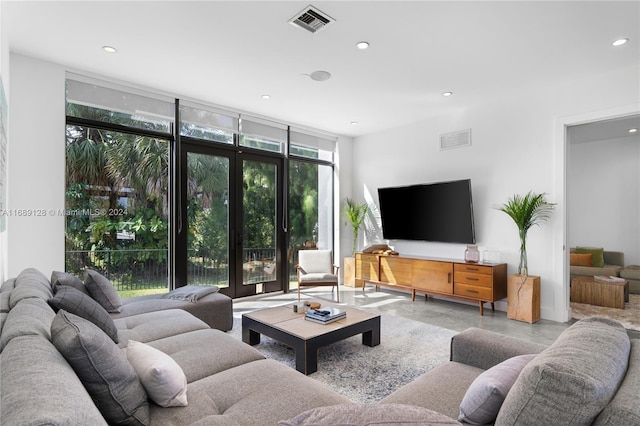 living room with concrete flooring, floor to ceiling windows, and a healthy amount of sunlight