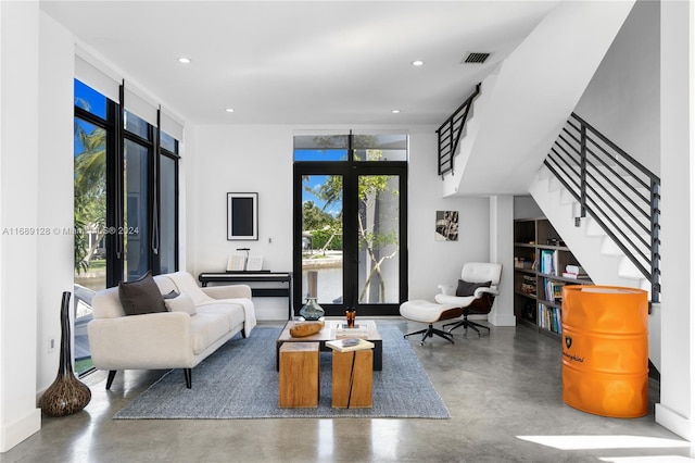 living room with expansive windows, concrete flooring, and french doors