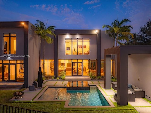 back house at dusk featuring french doors, an outdoor living space, and a patio area