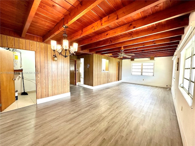 empty room with hardwood / wood-style floors, wood walls, wooden ceiling, ceiling fan with notable chandelier, and beam ceiling