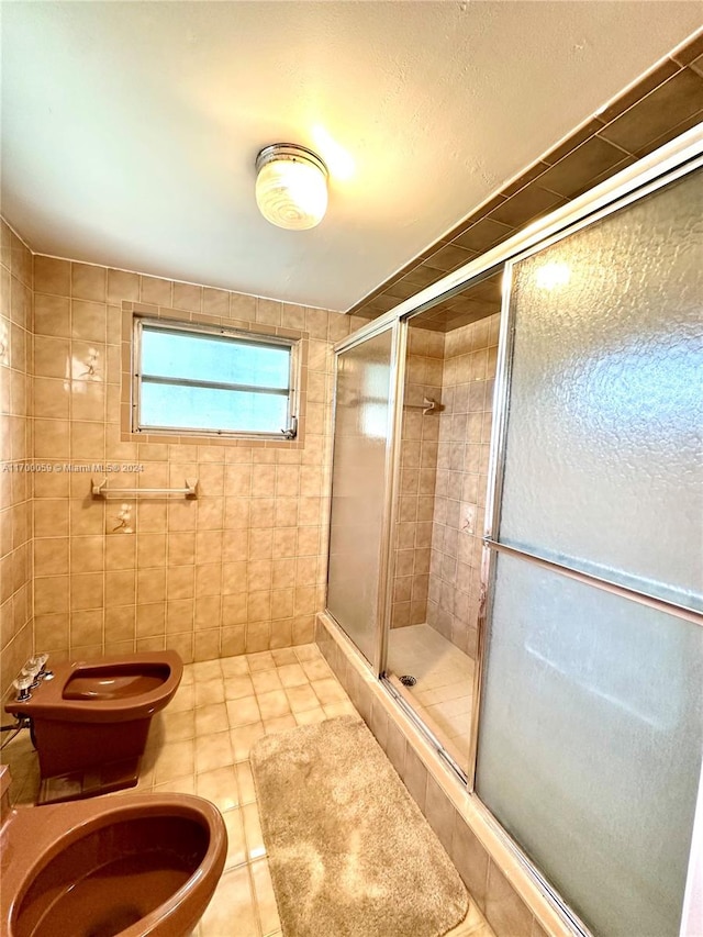 bathroom with tile patterned floors, toilet, a shower with shower door, and tile walls