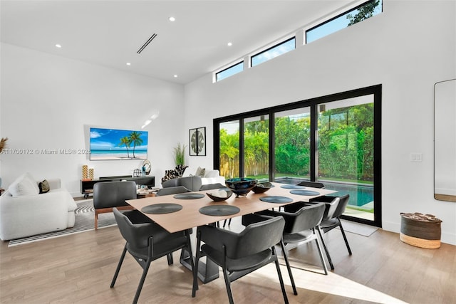 dining space featuring light hardwood / wood-style floors and a high ceiling