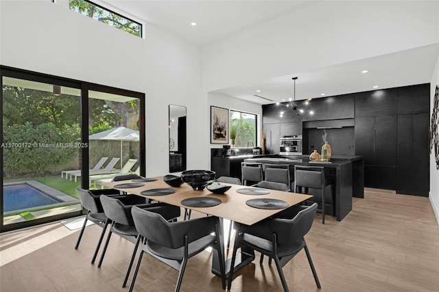 dining room with a towering ceiling and light hardwood / wood-style floors