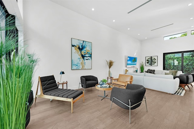 living room featuring a towering ceiling and light wood-type flooring