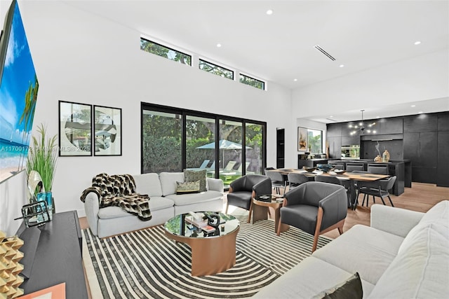 living room featuring light hardwood / wood-style floors, a healthy amount of sunlight, and a high ceiling