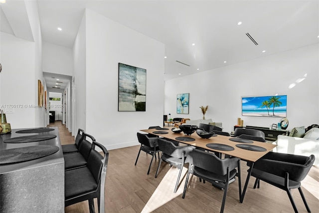 dining room featuring a towering ceiling and light hardwood / wood-style flooring